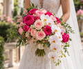 Bride holding bouquet of fuchsia and blush roses with cascading white Phalaenopsis orchids at elegant wedding
